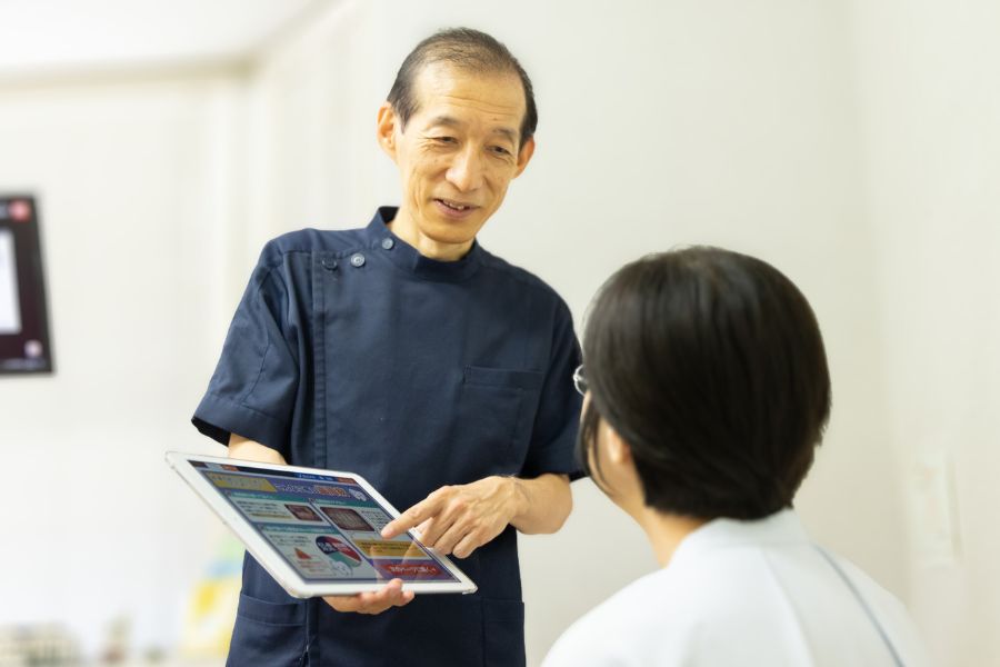 院長がiPadを使って患者さんに治療の説明をしている写真